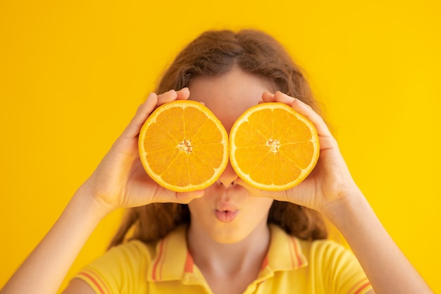 Kind met oranje helften in plaats van zonnebril.