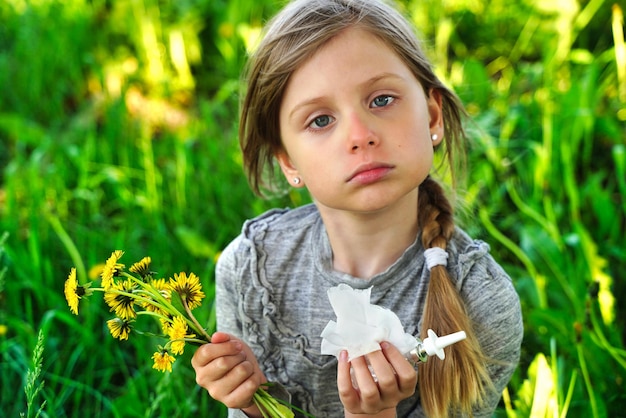 Kind met pollenallergie Meisje niezen en snuiten neus vanwege seizoensgebonden allergie Lenteallergie concept Bloeiende struiken en bomen op achtergrond Kinderallergie
