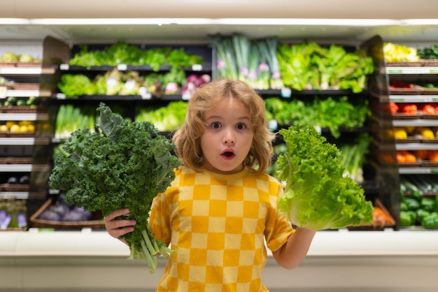 Kind met sla en groenten. Kind kiest fruit en groenten tijdens het winkelen bij groentenwinkel.