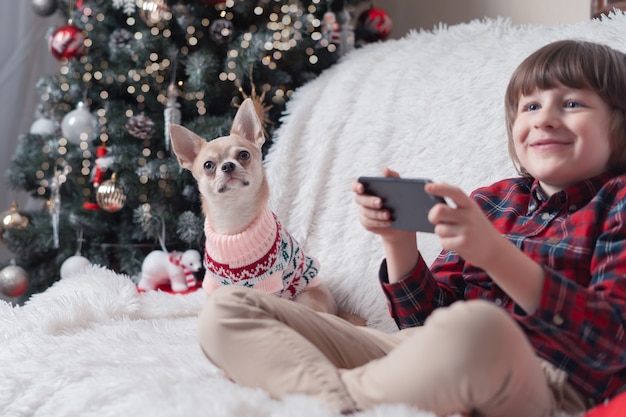 Kind met smartphone en zijn puppy met Kerstmis.