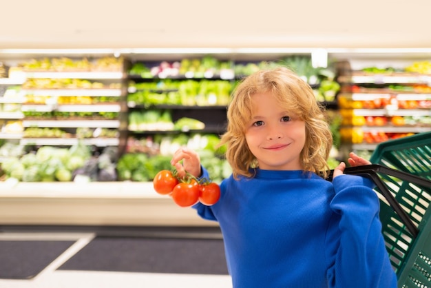 Kind met verse tomatengroenten portret van een kind in een levensmiddelenwinkel of een supermarkt klein kind goi