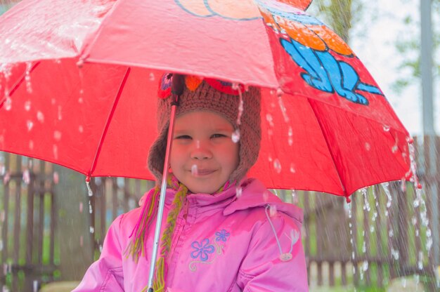 Kind onder een paraplu in de regen.