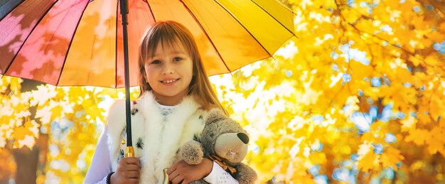 Kind onder een paraplu in het herfstpark Selectieve aandacht