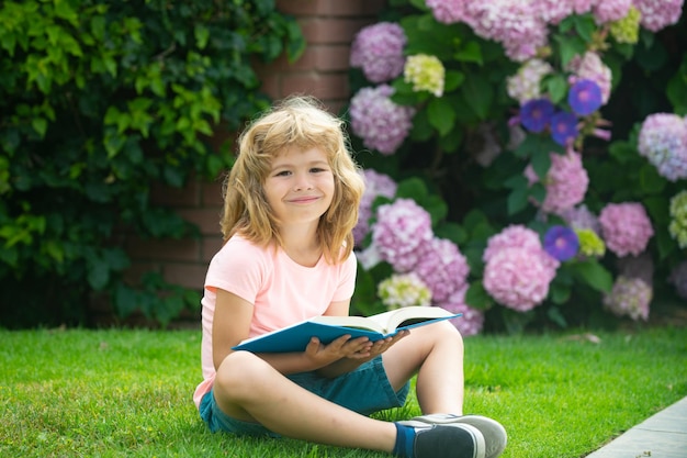 Kind ontspannen in de vakantie jongen lezen boeken over gras achtergrond leren concept