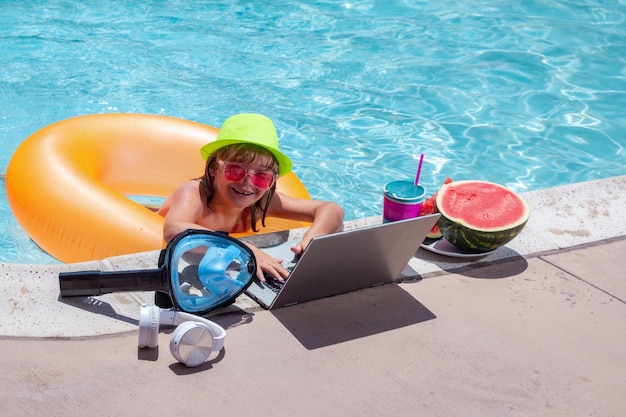Kind ontspannen in het zwembad met laptop Kid online bezig met laptop zwemmen in een zonnig turkoois waterzwembad Freelance werkafstand online werk e-learning