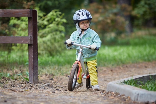 Kind op een loopfiets op een koude herfst- of zomerdag. Wanten op de handen.