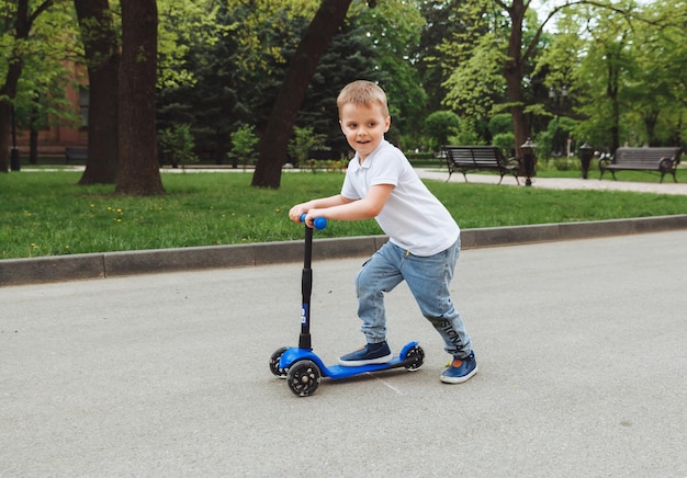 Kind op een scooter in het park Een kleine jongen rijdt op een scooter op een zonnige dag Actieve sporten voor kleuters