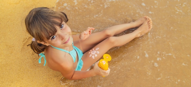 Kind op het strand met zonnebrandcrème op zijn rug