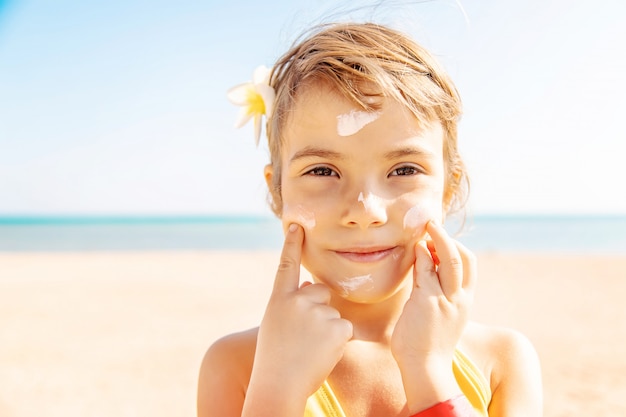 Kind op het strand smeert zonnebrandcrème. Selectieve aandacht.