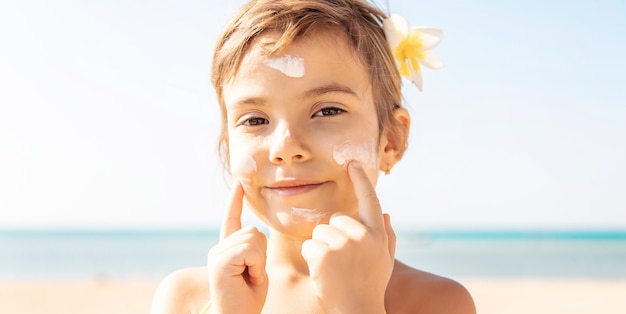 Kind op het strand smeert zonnebrandcrème