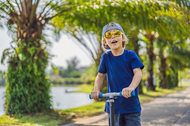 Kind op kick scooter in park Kinderen leren skate roller board Kleine jongen schaatsen op zonnige zomerdag Outdoor activiteit voor kinderen op veilige woonstraat Actieve sport voor voorschoolse jongen