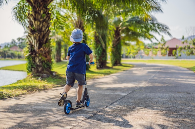 Kind op kick scooter in park Kinderen leren skate roller board Kleine jongen schaatsen op zonnige zomerdag Outdoor activiteit voor kinderen op veilige woonstraat Actieve sport voor voorschoolse jongen