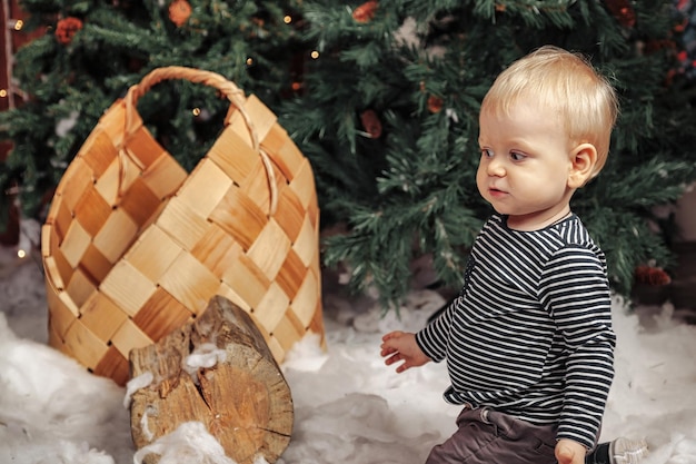 Kind op witte pluizige deken spelen door kerstboom