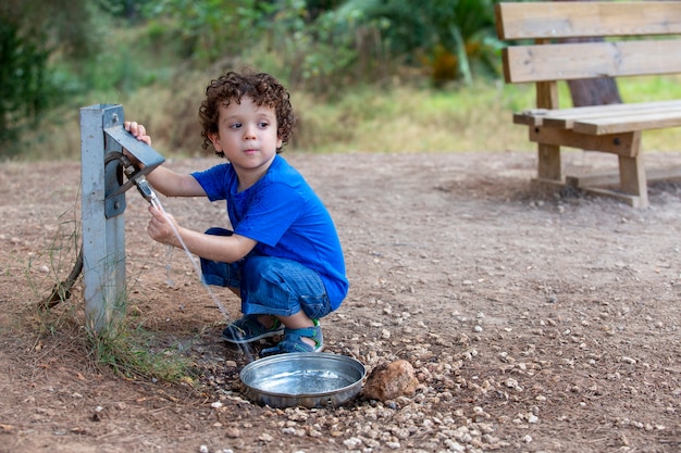 Kind opent een fontein voor dieren in een park midden in de natuur