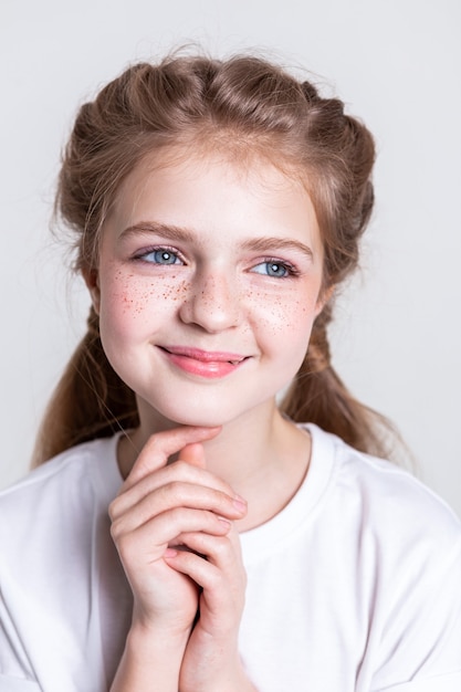 Kind opzoeken. Vrolijke jonge dame met ongewone sproeten op haar wangen die aangenaam lacht tijdens het fotograferen in de studio