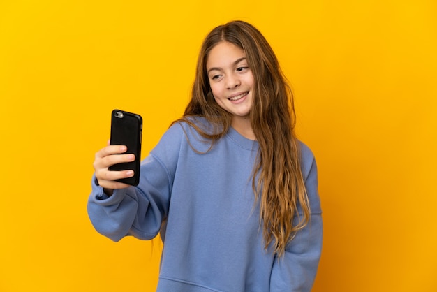 Kind over geïsoleerde gele muur die een selfie maakt