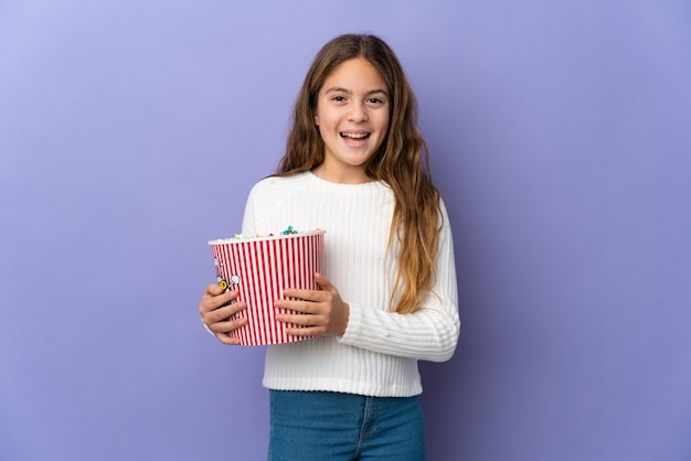 Kind over geïsoleerde paarse achtergrond met een grote emmer popcorns