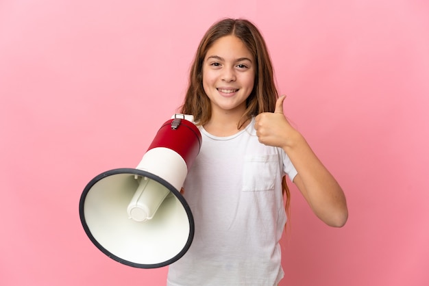 Kind over geïsoleerde roze achtergrond met een megafoon met duim omhoog