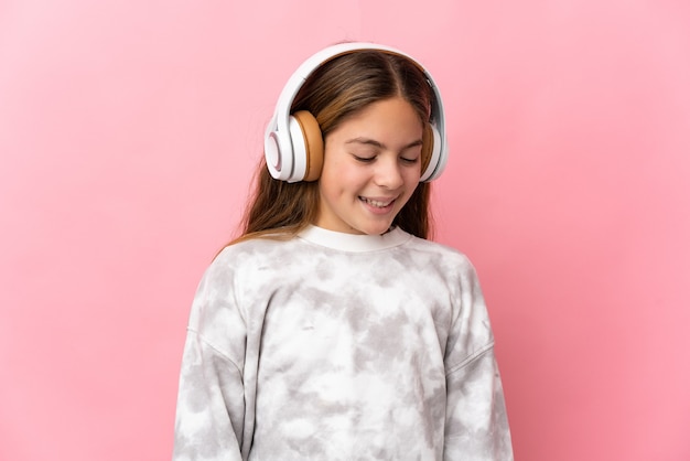 Kind over geïsoleerde roze achtergrond muziek luisteren