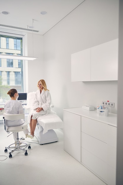 Foto gentile paziente seduta sul divano e guardando il suo medico, mantenendo il sorriso sul suo viso