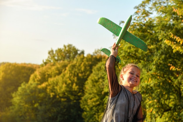 Kind piloot vlieger met vliegtuig droomt van reizen in de zomer in de natuur bij zonsondergang kinderen lopen gelukkig samen tijdens mooi zonnig weer in het park