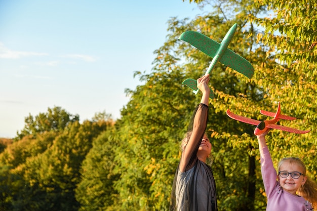 Kind piloot vlieger met vliegtuig droomt van reizen in de zomer in de natuur bij zonsondergang kinderen lopen gelukkig samen tijdens mooi zonnig weer in het park