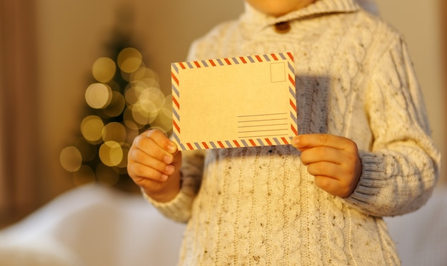 Foto kind plaatst een brief voor de kerstman populaire kinderen kerstactiviteit nieuwjaarsboom wazig