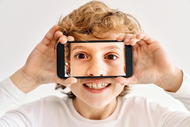 Kind poseert met zijn mobiele telefoon en foto's gemaakt van delen van zijn gezicht