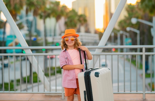 Kind reiziger met koffer buiten toerist kind jongen met vrolijke vakantiereis