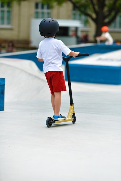 kind rijdt op een Kick-scooter. speeltuin voor het rijden op Kick scooter. skatepark. jonge beginnende atleet