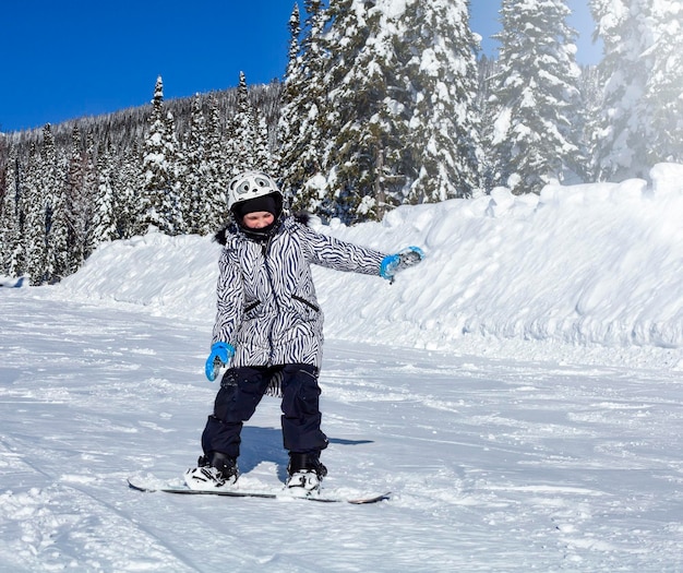 kind rijdt op een snowboard op een berghelling