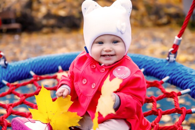 Kind rijdt op schommel met gele herfstbladeren