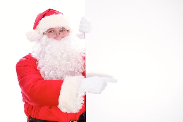 Kind Santa Claus pointing in white blank sign, isolated on white background.