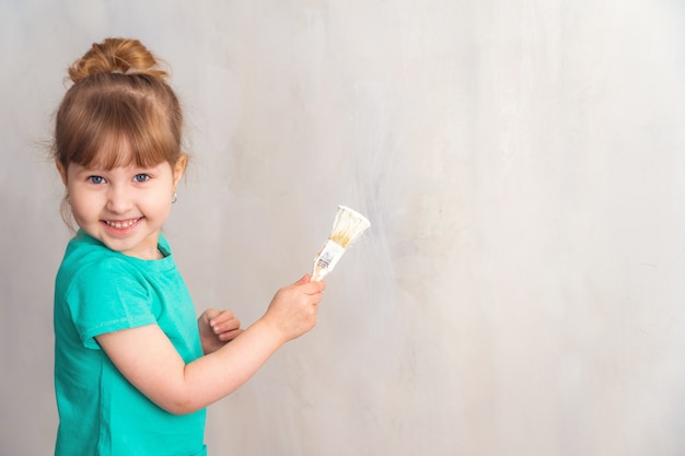 Kind schildert de muur met een witte kwast