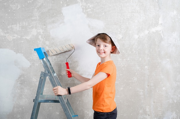 kind schildert een blauwe muur met een rollerreparatie