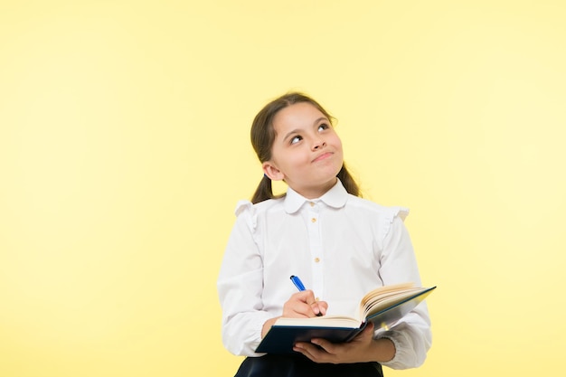 Kind schooluniform kind doet huiswerk Kind meisje schooluniform kleding houd boek en pen vast Meisje schattig notities voor ideeën opschrijven Notities om te onthouden Schrijf essay of notities Persoonlijk schema Notities maken