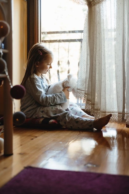 Kind speelt bij het raam thuis dromerig