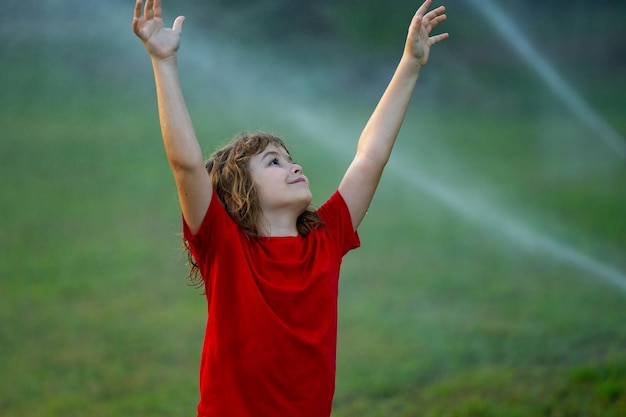Kind speelt in de achtertuin in de zomer water plezier in de tuin kind speelt met water sprinkler in de tuin grappig l