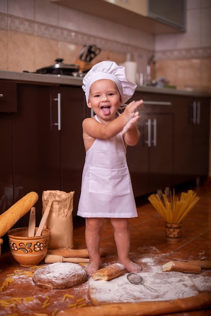 kind speelt met meel in de keuken verkleed als kok