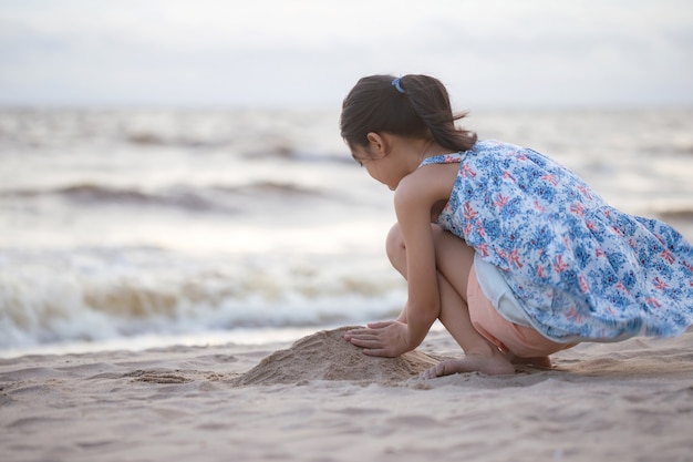 Kind speelt met zand op het strand Klein meisje speelt 's avonds buiten