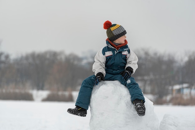 Kind spelen in sneeuwkasteel. Portret van jongen op groot blok sneeuw in winterpark.