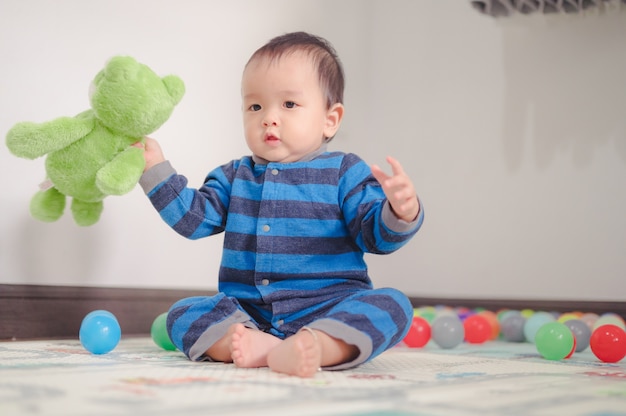 Kind spelen met ballen en groene teddybeer op zacht tapijt