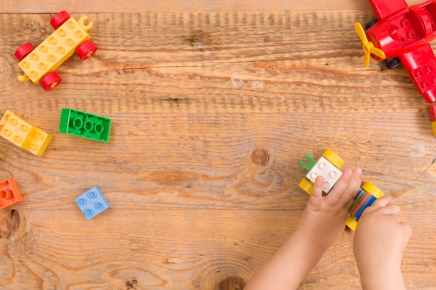 Kind spelen met kleurrijke speelgoed bakstenen op houten achtergrond