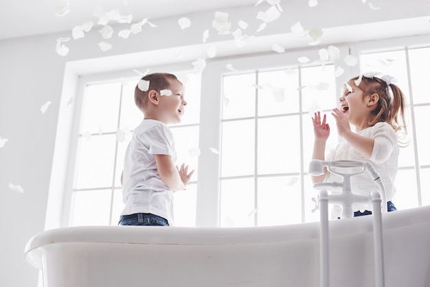 Kind spelen met rozenblaadjes in huis badkamer. Klein meisje en jongen fawing plezier en vreugde samen. kindertijd en de realisatie van dromen, fantasie, verbeelding