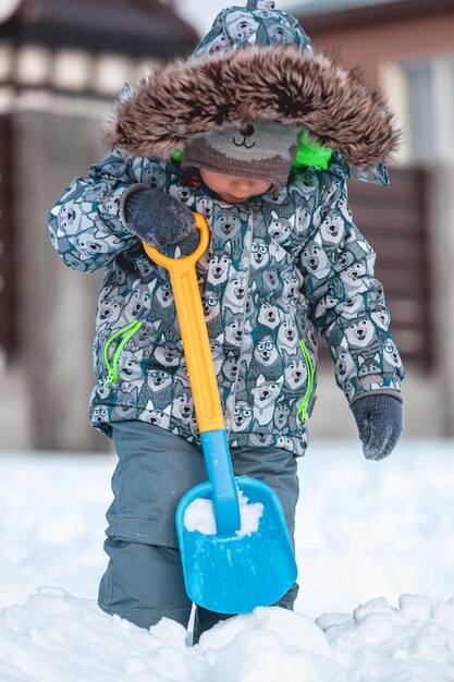 Kind spelen met schop in de sneeuw op de zonnige winterdag