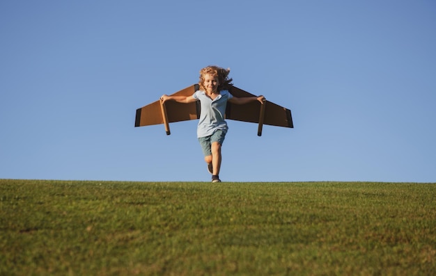 Kind spelen met speelgoedvliegtuigvleugels in zomerpark innovatietechnologie en succesconcept kinderpilo...