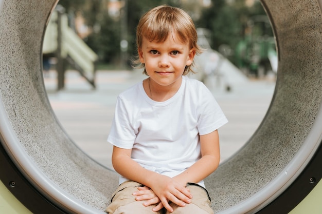 Kind spelen op de speelplaats van de stad op ring rond schattige kleine gelukkig lachende openhartige vijf jaar oude kind jongen met lang blond haar in een witte tshirt generatie z kinderen geestelijke gezondheid levensstijl