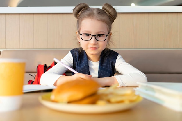 Kind studeert schoolmeisje voor lunchpauze ongepast ongezond dieet fastfood kinderen