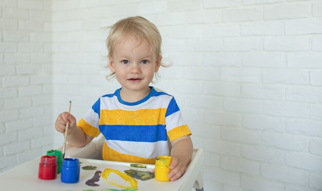 kind tekenen met verf, glimlach spelen. peuter met educatief speelgoed voor creativiteit. jongen spelen thuis