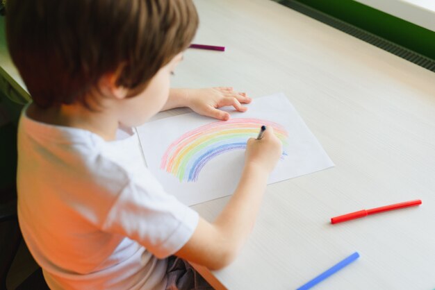 Kind tekening met kleurrijke regenboog